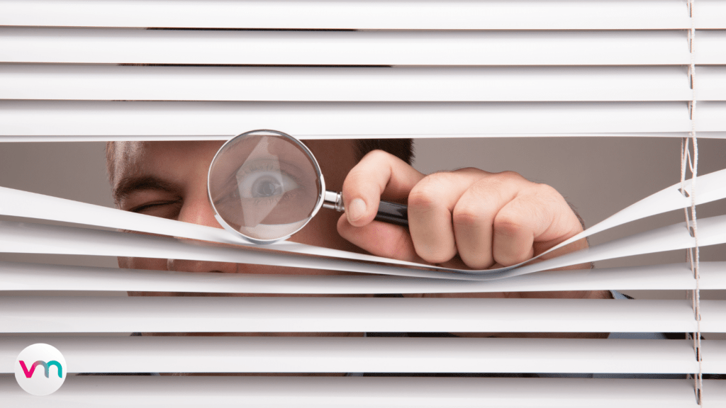 a young man looking through window blinds